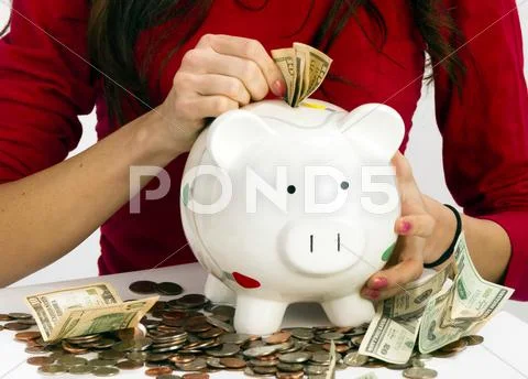 Woman stuffing us currency coins piggy bank cash savings Stock Photos