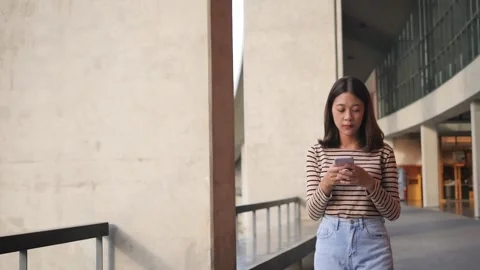 A woman succeeds using a smartphone while walking down the street in front of a  Stock Footage 201363177
