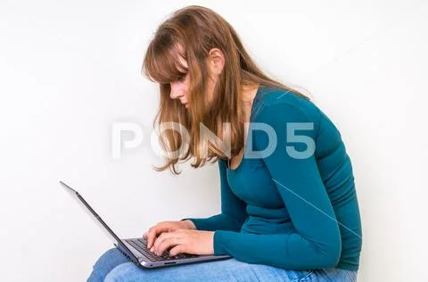 Woman is suffering from back pain sitting with laptop - concept of bad posture Stock Photos