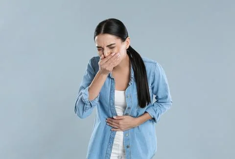 Woman suffering from stomach ache and nausea on grey background. Food poisoni Stock Photos