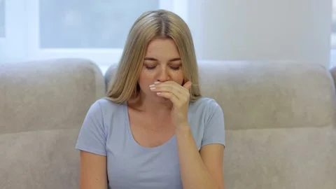 A woman suffers from allergies or the flu. The girl got sick and sneezes at h Stock Footage 169765702