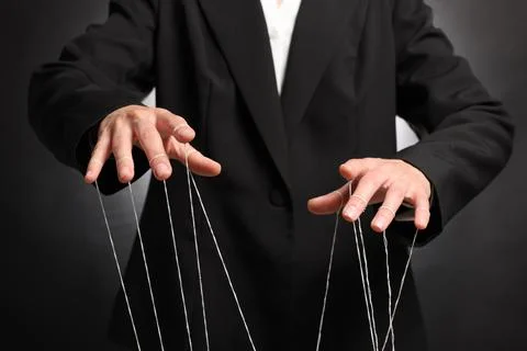 Woman in suit pulling strings of puppet on dark background, closeup 스톡 사진