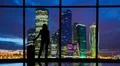 The woman with suitcase stands near the windows in the business office buildi Photo