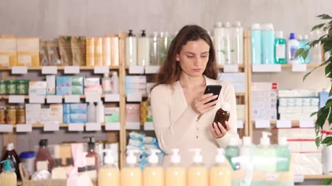 Woman in summer clothes scans code on cough syrup to check the expiration date Stock Footage 331298169