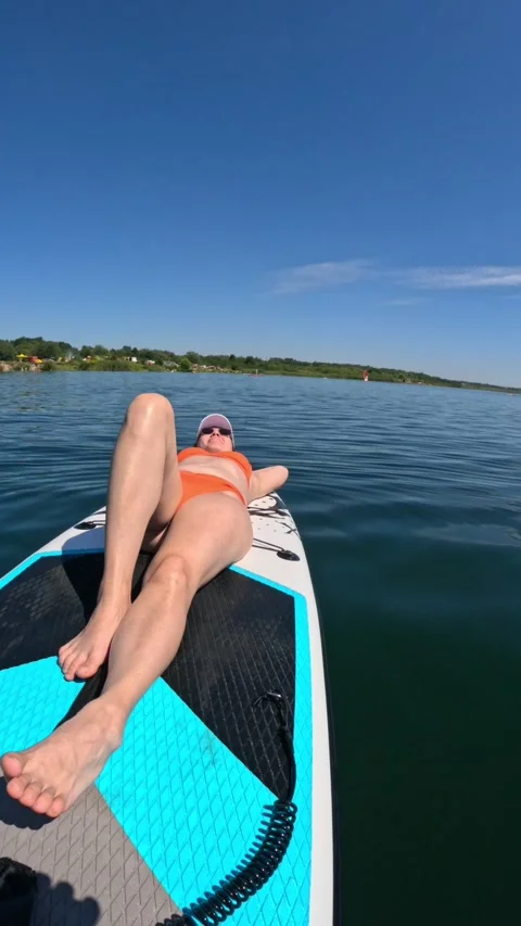Woman sunbathing while floating on supboard Stock-Footage 261514217
