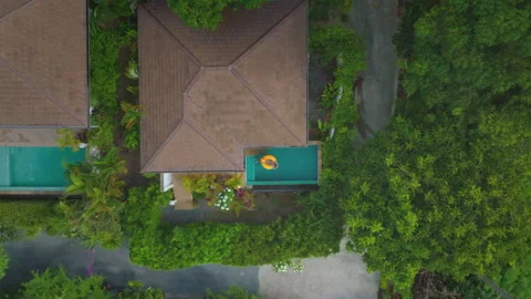 Woman sunbathing on yellow pool float in tropical resort pool - aerial view Stock Footage 311111470