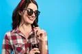 The woman in sunglasses standing with a bottle of drink on the blue backgroun Photo