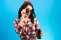 The woman in sunglasses standing with a bottle of drink on the blue backgroun Photo
