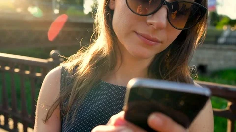 Woman in sunglasses talking on the smartphone while walking down the street at Stock Footage