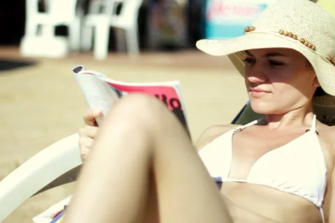 Woman in a Sunhat Reading by Pool Stock Footage 1068332