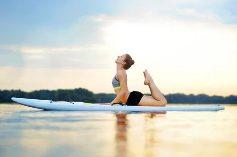Woman on sup board practicing cobra yoga pose Stock Photos