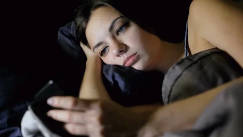Woman surfing internet while lying in bed in the bedroom at night, looks photo Stock Footage 99077485
