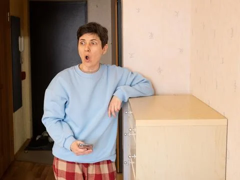 Woman surprised by message while using smartphone at home Stock Photos