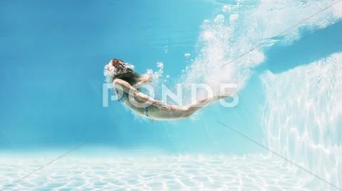 Woman swimming underwater in swimming pool Stock Photos