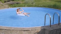 Two Women Are Relaxing In Pool On Air Mattress Are Drinking