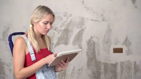 Woman with tablet computer on background of renovation in new house. Vidéo 144452430