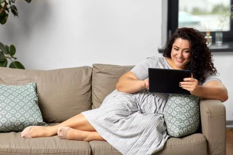 Woman with tablet pc computer on sofa at home Stock Photos