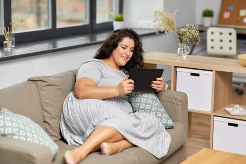 Woman with tablet pc computer on sofa at home Stock Photos