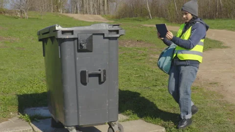 Woman is with a tablet PC at a garbage container Stock Footage 333503348