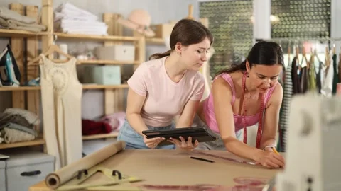 Woman tailor draw dress pattern of product on paper and participate in creating Stock Footage 345565372