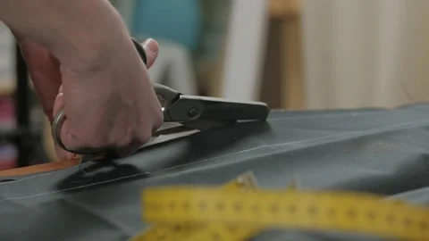 A woman, a tailor of a sewing workshop on the table cuts fabric with scissors. Stock Footage 148191054