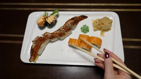 Woman take roll from plate with sushi, using chopsticks, first person view Stock Footage