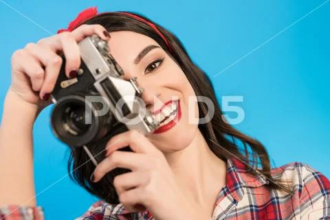 The woman takes a photo with an retro camera on the blue background Stock Photos
