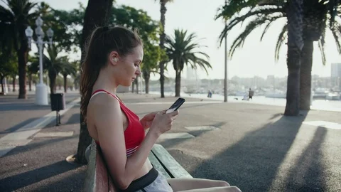 Woman taking break after work out checking train programme on a smartphone app Stock Footage 100421685