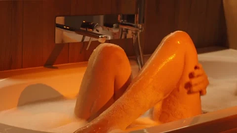 Woman taking bubble bath in cozy bathroom with romantic lighting Stock Footage 313838231