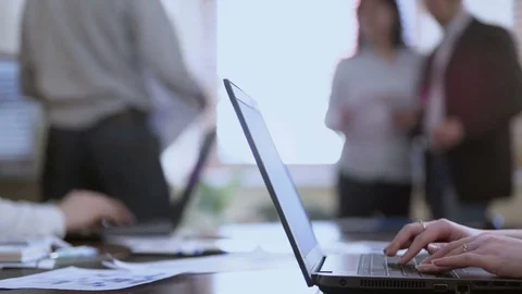 Woman taking concise notes on laptops, male joining two colleagues in discussion Stock Footage 76167048