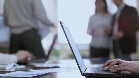 Woman taking concise notes on laptops, male joining two colleagues in discussion Stock Footage 76169845
