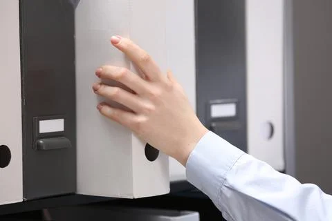 Woman taking folder with documents from shelf in office, closeup Foto stock