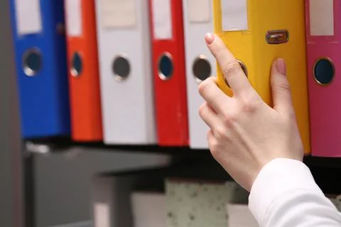 Woman taking folder with documents from shelf in office, closeup Foto stock
