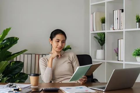 Woman taking note in notebook while using laptop at home. business woman writing Foto stock