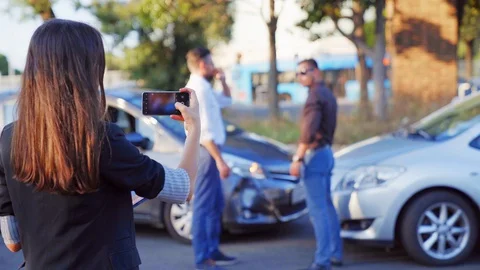 Woman taking notes and taking photo of car accident on mobile phone. Two drivers Stock Footage 94990747