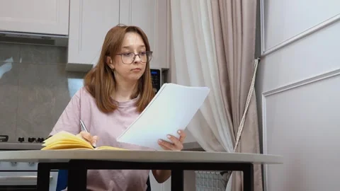 Woman taking notes from documents at home Stock Footage 314622388