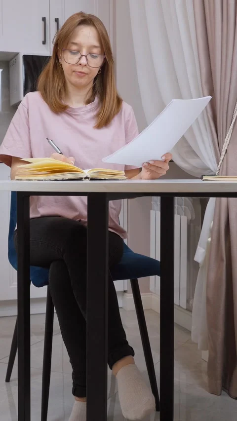 Woman taking notes from documents at home Stock Footage 314648373