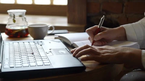 Woman Taking Notes in a Notebook and Using Laptop Stock Footage 110999087