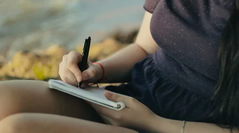 Woman taking notes in a notebook sitting on the coast 스톡 동영상 65826868