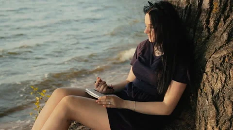 Woman taking notes in a notebook sitting on the coast 스톡 동영상 65826954
