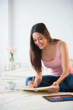 Woman taking notes with tablet computer on bed 스톡 사진
