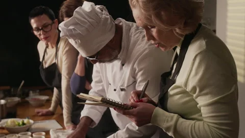 Woman Taking Notes While Attending Group Cooking Master Class Stockbeeldmateriaal 332572139