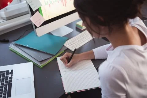 Woman taking notes while sitting on her desk 스톡 사진