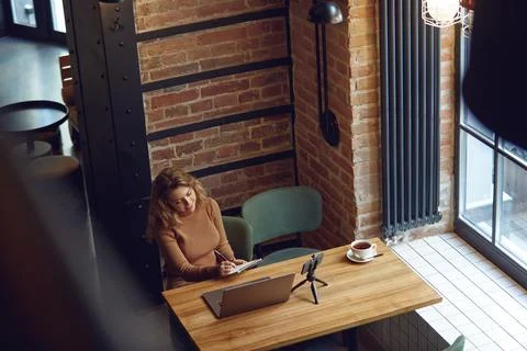 Woman taking notes while working on laptop Stock Photos