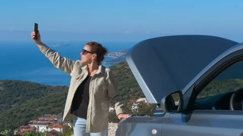Woman taking selfie with broken down car on a road trip Stock Footage 344956865