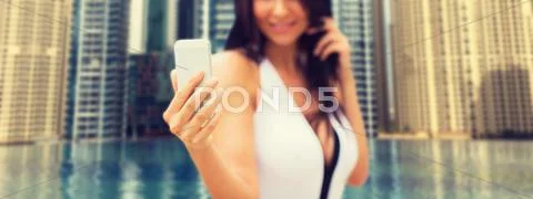 Woman taking selfie with smartphone over city pool Stock Photos
