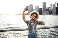 Woman Taking Selfie Through Mobile Phone While Standing Against River Stock Photos