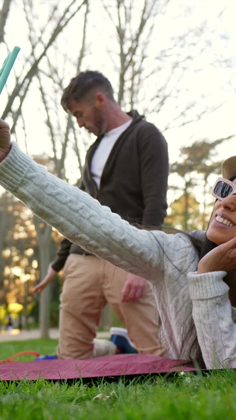 Woman taking selfie while man dancing funny in the park Vídeos de archivo 333235278