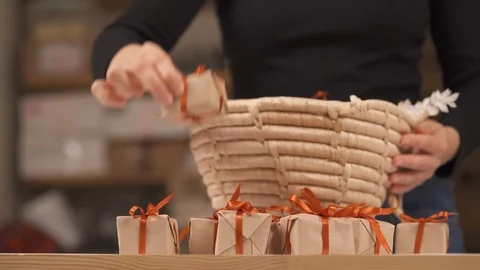 Woman taking tiny gift boxes with decorative wrapping out of wicker basket. 스톡 동영상 119759583