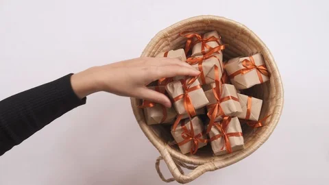 Woman taking tiny gift boxes with decorative wrapping out of wicker basket. 스톡 동영상 119759672